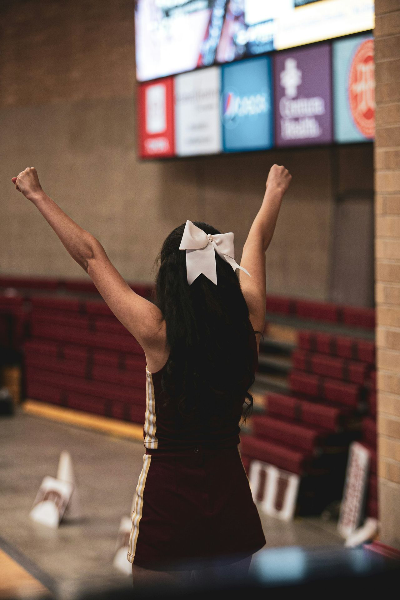 Cheerdancerin mit erhobenen Armen in einer Turnhalle